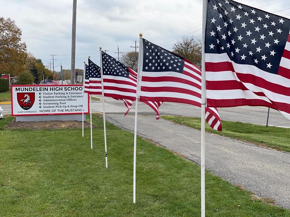 Several American flags on display in front of Mundelein High School