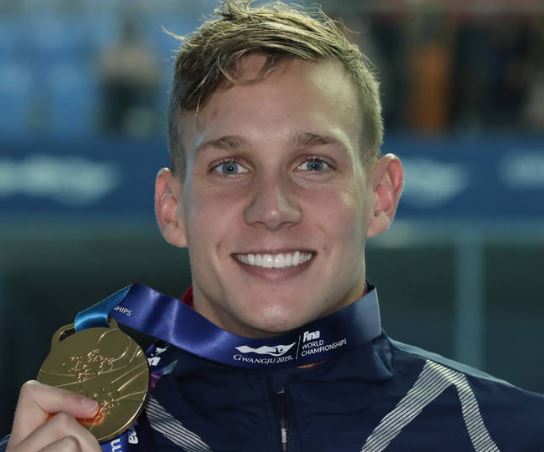 Caeleb Dressel smiling while holding his gold medal