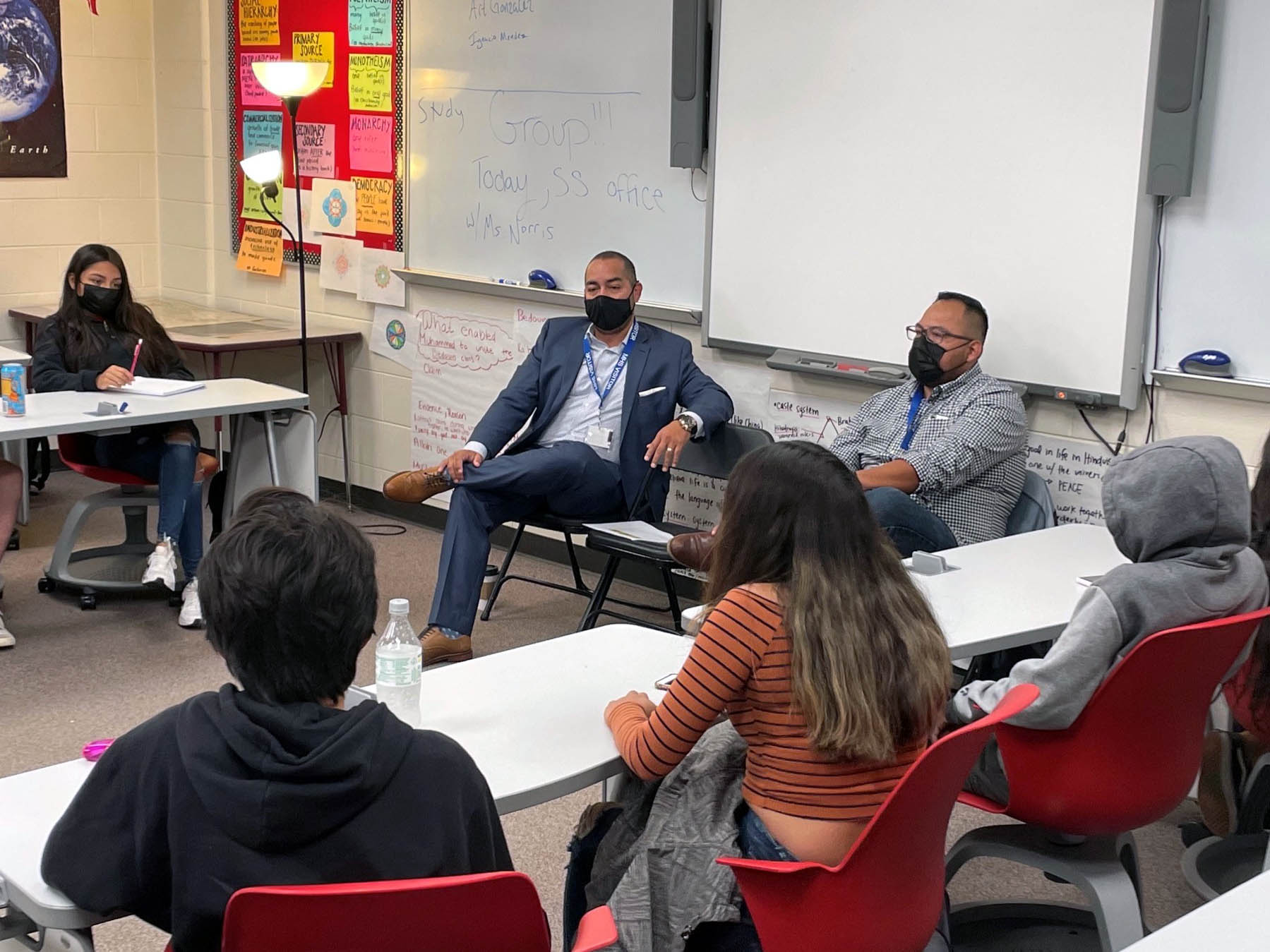 Ignacio Mendez and  Art Gonzales sitting in chairs and speaking to freshmen at MHS..