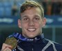 Caeleb Dressel smiling while holding his gold medal