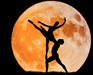 Silhouette of couple dancing in front of a yellow moon
