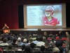 Mark Hilinski speaks from a podium with an image of his son on the big screen behind him.