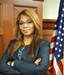 Photo of Zaneta standing in a courtroom with the US Flag to her side