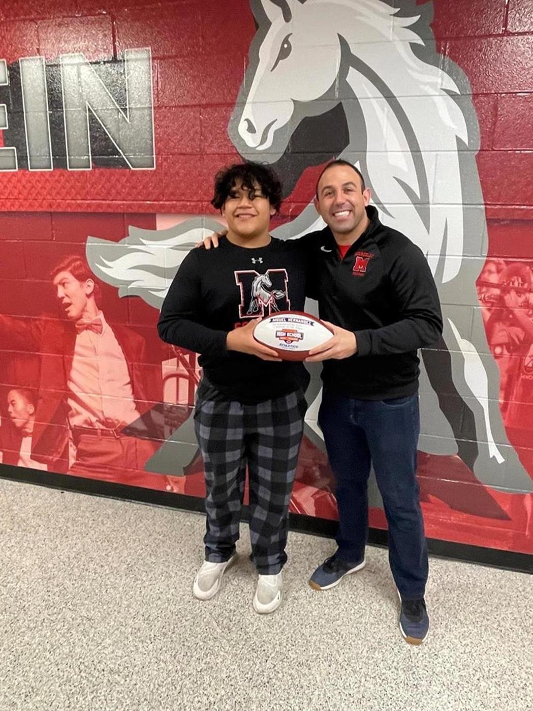 Miguel Hernandez poses with MHS Football Coach Vince DeFranceso with the football awarded to him by the Chicago Bears.