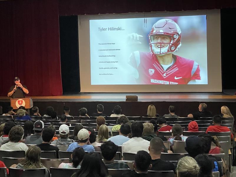 Mark Hilinski speaks from a podium with an image of his son on the big screen behind him.
