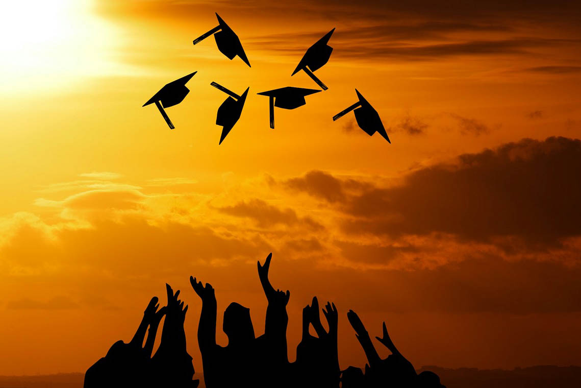 silhouette of graduates throwing their caps into the air
